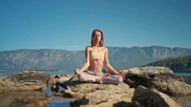 Doğada kadın yogası, güzel deniz ve dağ manzarası, Lotus 'ta taş üstünde oturan kız.