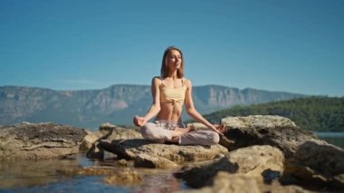 Dikiz aynasındaki kadın, dağların arasındaki sakin sahilde yoga ve meditasyon yapıyor. İç benliğe bağlan ve doğayla uyum sağla.