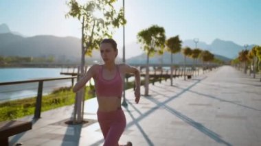 Yavaş çekim. Spor salonundaki kendine güvenen kadın parkta koşuyor. Moove üzerindeki koşucu kız konsantrasyonunun portresi.