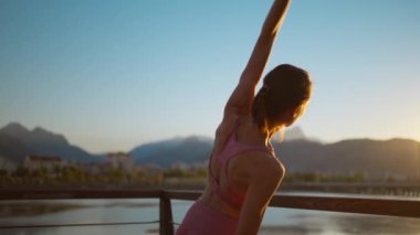 Altın güneş ışığı arka planında sağlıklı bir kadın yogası portresi. Sabah egzersiz pozu için kollarını aç..