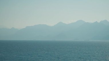 Türkiye 'nin Antalya kıyı şeridinde gün ortası manzarası - Akdeniz ve karlı dağ sırasının hava perspektifinde görünümü