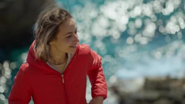 Portret Szczęśliwej Młodej Kobiety Podróżującej Jasnoczerwonej Kurtce Siedzącej Krawędzi Klifu — Wideo stockowe