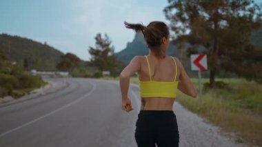 Ağır çekimde Genç Atletizm Kadını Hızlı Koşarken, Sıkı Antrenman Yaparken, Yarış Yarışması ya da Maraton İçin Hazırlanırken. Siyah şortlu fit kız Şafakta Yeşil Tarlalar boyunca koşuyor.