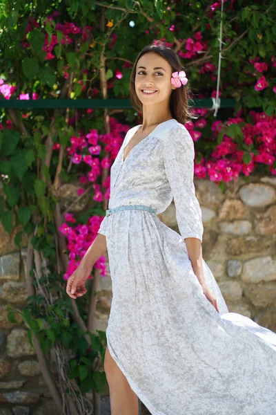穿着白色衣服的优雅的年轻女子喜欢散步 背景上绽放着粉红色的花朵 — 图库照片