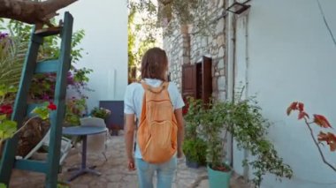 Sırt çantalı, gülümseyen güzel turist kadın turist şehrin eski turistik bölgesinde boş bir sokakta yürüyor ve Türkiye 'nin Marmaris kentinde tatilin tadını çıkarıyor. Popüler turizm merkezini gezmek