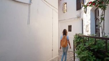 Sırt çantalı, gülümseyen güzel turist kadın turist şehrin eski turistik bölgesinde boş bir sokakta yürüyor ve Türkiye 'nin Marmaris kentinde tatilin tadını çıkarıyor. Popüler turizm merkezini gezmek