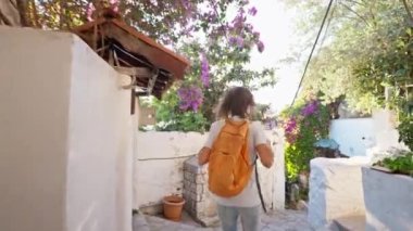 Sırt çantalı, gülümseyen güzel turist kadın turist şehrin eski turistik bölgesinde boş bir sokakta yürüyor ve Türkiye 'nin Marmaris kentinde tatilin tadını çıkarıyor. Popüler turizm merkezini gezmek