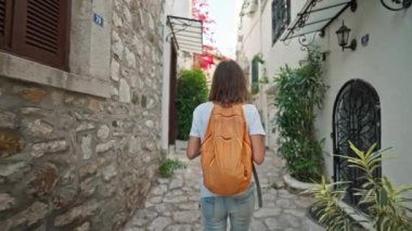 Sırt çantalı, gülümseyen güzel turist kadın turist şehrin eski turistik bölgesinde boş bir sokakta yürüyor ve Türkiye 'nin Marmaris kentinde tatilin tadını çıkarıyor. Popüler turizm merkezini gezmek
