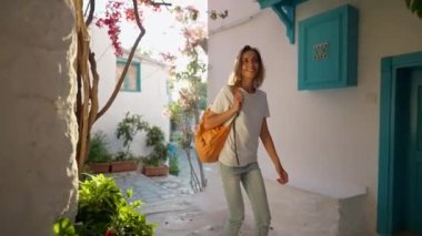 Sırt çantalı, gülümseyen güzel turist kadın turist şehrin eski turistik bölgesinde boş bir sokakta yürüyor ve Türkiye 'nin Marmaris kentinde tatilin tadını çıkarıyor. Popüler turizm merkezini gezmek