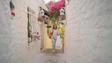 Sırt çantalı, gülümseyen güzel turist kadın turist şehrin eski turistik bölgesinde boş bir sokakta yürüyor ve Türkiye 'nin Marmaris kentinde tatilin tadını çıkarıyor. Popüler turizm merkezini gezmek