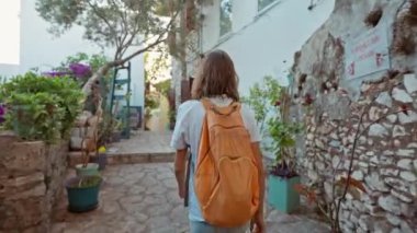Sırt çantalı, gülümseyen güzel turist kadın turist şehrin eski turistik bölgesinde boş bir sokakta yürüyor ve Türkiye 'nin Marmaris kentinde tatilin tadını çıkarıyor. Popüler turizm merkezini gezmek