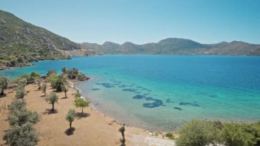 Turkuaz suyu ve cennet gibi boş deniz plajları olan güzel körfezin kıyısında turuncu elbiseli çekici, bronz tenli kadın gezgin duruyor. Kız Türkiye 'nin Marmaris bölgesinde deniz kıyısında yürüyor