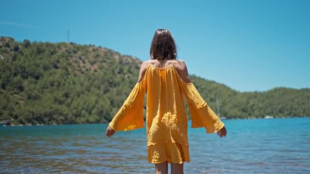 Bekymmerslös Kvinna Orange Solklänning Med Öppna Armar Stående Stranden Njuta — Stockvideo