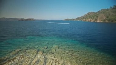 Sırt çantalı çekici, ince kadın gezgin turkuvaz suyu ve cennet gibi boş deniz plajlarıyla güzel bir deniz koyunda yürüyor. Ağır çekim 4k, Türkiye 'de seyahat