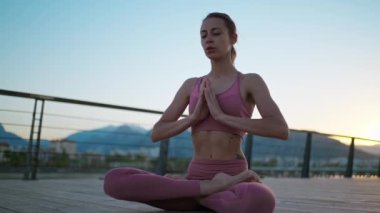Sıska kadın gün batımında yogada oturur deniz kenarında, pratik yapar, egzersiz yapar, sağlıklı bir vücut.