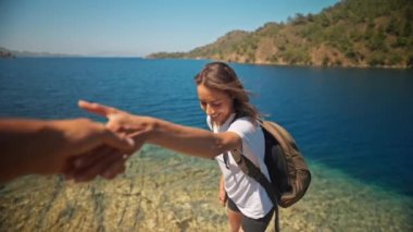 POV gülümseyen çekici, ince kadın gezgin sırt çantalı güzel deniz koyunun uçurumunda berrak turkuaz suyla yürüyor. Kadın elini uzatıp yardım istiyor. Ağır çekim 4k, Türkiye 'de seyahat