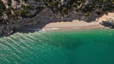 Yukarıdan bakıldığında, günbatımında turkuaz dalgalı bir deniz ile yıkanan güzel bir plajda güneşlenen bazı turistlerin çarpıcı hava manzarası. Türkiye 'nin Antalya kentindeki Akdeniz kıyı şeridi.