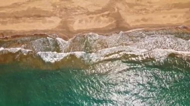 Deniz ya da okyanus sörf dalgası. Haddeleme ve bir kum plajı üzerinde geliyor köpüklü okyanus dalgaları. Hava yukarıdan aşağı atış, 4k