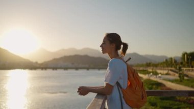 Güzel bir genç kadının portresi. Dağlar ve günbatımı gökyüzü ile doğanın tadını çıkarıyor. Manzarada rahatlıyor.