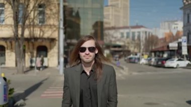 Modern ofis binasına yürürken takım elbise giyen düşünceli iş adamının portresi. Genç bir girişimci gökdelenlerin yakınındaki şehir merkezine bakıyor.