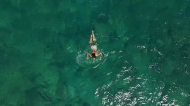 Havadan görünümü. Güzel genç kadın beyaz bikini berrak Turkuaz rengi okyanus su yüzeyinde yüzen