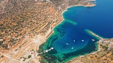 Yukarıdan bakıldığında, şeffaf ve turkuaz deniz manzaralı birkaç tekne ve yatla. Akdeniz kıyıları, Knidos Antik kenti, Datca, Türkiye. Yaz tatili ve deniz kenarına seyahat