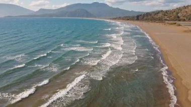 Güneş doğarken tropikal beyaz kum plajı üzerinde uçan hava manzarası, Iztuzu Kaplumbağa Sahili, Türkiye