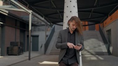 Modern Smartphone kullanan, Business Center 'ın yanında duran sıradan kıyafetli bir adam. Mesajlar Yazan, Cep Telefonu gezen, Sosyal ağlarda sohbet eden ve arama yapan adam