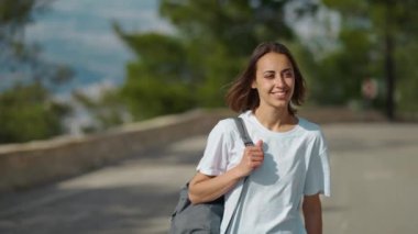 Dağın tepesindeki platformda, mavi arka plan vadisinin manzarasıyla yazı için gezen kadın turist. Moda elbiseli genç kız dağdan manzaranın tadını çıkarıyor.