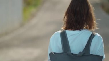 Dağın tepesinde mavi arka plan vadisi manzarasıyla yürüyen bir kadın gezgin. Günlük kıyafetler ve sırt çantalı genç turist kız dağdan manzaranın keyfini çıkarıyor.