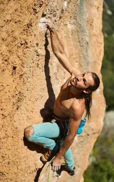 Rock climbing moments. Top view of beautiful athletic male confidently looking up on rock