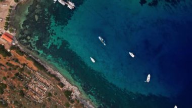 Yukarıdan bakıldığında, şeffaf ve turkuaz deniz manzaralı birkaç tekne ve yatla. Akdeniz kıyıları, Knidos Antik kenti, Datca, Türkiye. Yaz tatili ve deniz kenarına seyahat