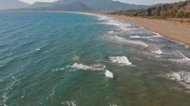 Güneş doğarken tropikal beyaz kum plajı üzerinde uçan hava manzarası, Iztuzu Kaplumbağa Sahili, Türkiye