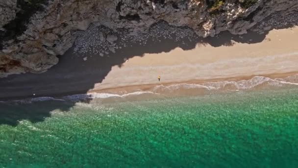 上からの眺めは 日没時にターコイズブルーの荒海に浴する美しいビーチで日光浴をする観光客の素晴らしい空撮ビュー トルコのアンタルヤの地中海沿岸 — ストック動画