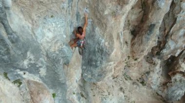 Gerl tırmanışçısı dayanır, çaba sarf eder. Sportif zinde bir kadının hava görüntüsü kayaya tırmanma rotasında dikey uçurumda, kaya tırmanışında, sinematik yavaş çekim kaya tırmanışı anlarında