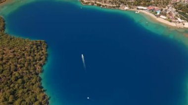 Fethiye 'deki Oludeniz yarımadasının muhteşem hava manzarası, mavi lagün, kumlu sahil üzerinde İHA uçuşu, turkuaz deniz, güneş yatakları ve şemsiyeli sahil beldesi, sıcak yaz günü..