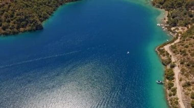Fethiye 'deki Oludeniz yarımadasının muhteşem hava manzarası, mavi lagün, kumlu sahil üzerinde İHA uçuşu, turkuaz deniz, güneş yatakları ve şemsiyeli sahil beldesi, sıcak yaz günü..
