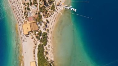 Fethiye 'deki Oludeniz yarımadasının muhteşem hava manzarası, mavi lagün, kumlu sahil üzerinde İHA uçuşu, turkuaz deniz, güneş yatakları ve şemsiyeli sahil beldesi, sıcak yaz günü..