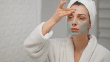 Çekici bir kadın yüz kremi sürüyor. Banyo aynasına bak. Sağlıklı genç bayan havlusunu başına sar.