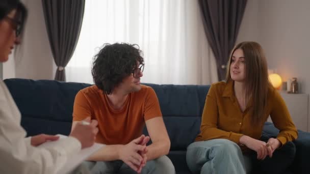 若いカップルは心理学者の前でソファに座って 彼らの関係の問題を議論し 作業する 関係の課題を克服するための専門家の助け — ストック動画