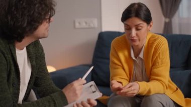 Psikolojik boşaltımda rahat koltukta oturan sıkıntılı genç bir kadının sorunlarından bahsedişinin yan görüntüsü. Ofisteki hastayı dinleyen profesyonel psikolog..