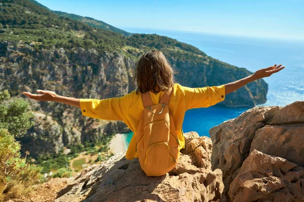 Nuori Nainen Turisti Istuu Kalliolla Oranssi Reppu Vapaus Avaamalla Aseita — kuvapankkivalokuva