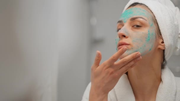迷人的女人在浴室镜子里用护肤霜在脸上看 健康的年轻女士用毛巾在头上放润肤升华面霜 健康的护肤理念 — 图库视频影像