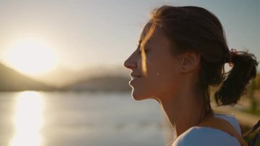 Güzel bir genç kadının portresi. Dağlar ve günbatımı gökyüzü ile doğanın tadını çıkarıyor. Manzarada rahatlıyor.