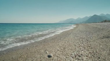 slow motion footage tropical island and sea waves crashing and foaming against pebble rocky beach. rocks coast meeting deep blue ocean water. Tourism in Turkey concept