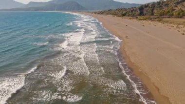 Güneş doğarken tropikal beyaz kum plajı üzerinde uçan hava manzarası, Iztuzu Kaplumbağa Sahili, Türkiye