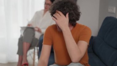 Kafkasyalı bir adam kanepeye uzanıp sorunları anlatırken kadın psikoloğu terapi sırasında sakinleşmesine yardım ediyor.