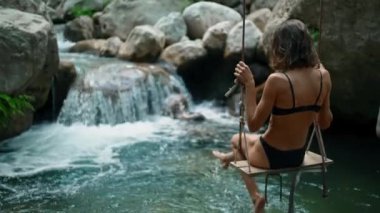 Siyah mayo giymiş güzel, sıska kız Bali 'deki şelalede eğleniyor. Seyahat ve yabani doğa kültürü hakkındaki kavram.