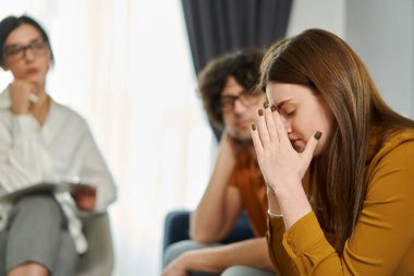 Üzüntülü kadın portresi, psikoterapistle terapi seansında umutsuzluk hisseden elleri ile yüzünü kapatıyor. Evlilik Psikoterapisi