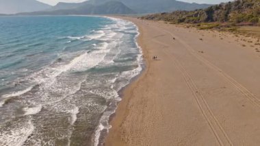 Güneş doğarken tropikal beyaz kum plajı üzerinde uçan hava manzarası, Iztuzu Kaplumbağa Sahili, Türkiye